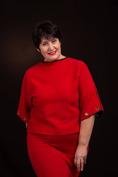Studio shot of a senior adult  smiling woman wearing a red dress - 写真・画像