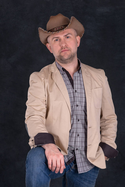 Studio schoot serieuze man in een cowboy hoed op donkere achtergrond.  - Foto, afbeelding
