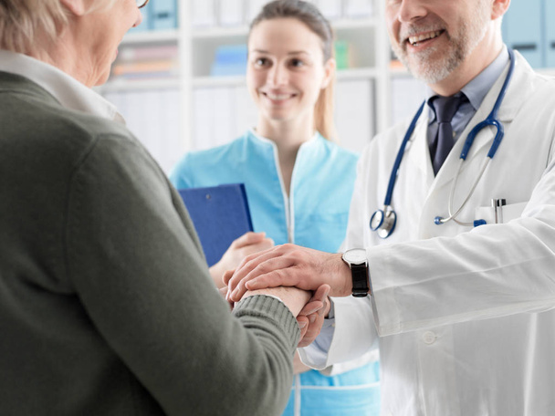 Professional doctor holding a senior patient's hands - Foto, afbeelding
