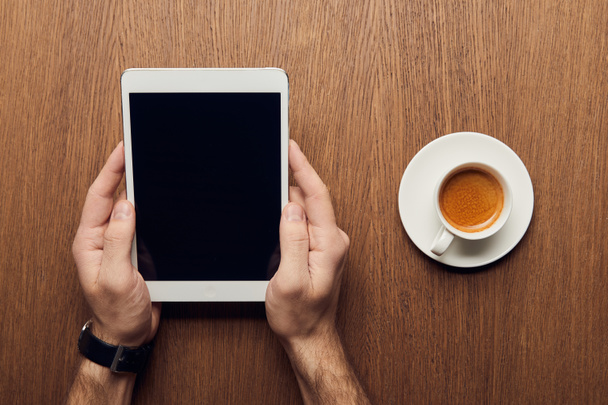 vista recortada del hombre sosteniendo tableta digital con pantalla en blanco cerca de la taza de café
 - Foto, Imagen