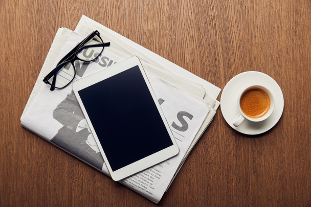 vista superior del periódico cerca de la taza con café, tableta digital con pantalla en blanco y vasos
 - Foto, Imagen