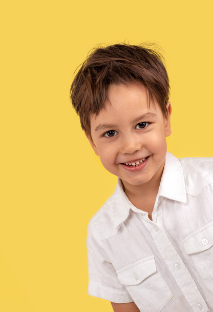 Estudio de un niño riendo en una camiseta blanca en un bac amarillo
 - Foto, imagen