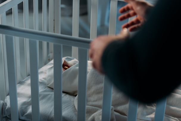 Cropped view of criminal kidnapping newborn child from crib - Photo, Image