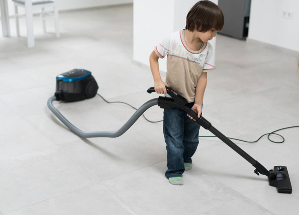 Kleine jongen doen vacuüm reiniging thuis binnenshuis - Foto, afbeelding