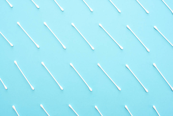 White cotton buds lie in a row on a blue background. - Φωτογραφία, εικόνα