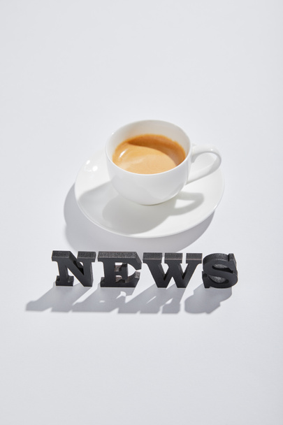 black news lettering near cup with coffee on white  - Foto, imagen
