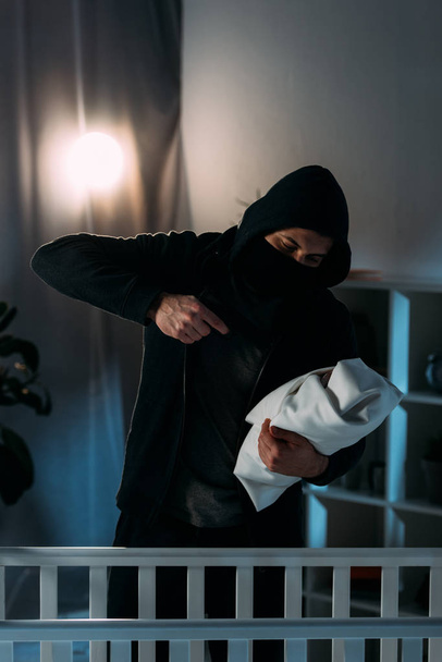 Απαγωγέας στα μαύρα ρούχα με στόχο το όπλο σε βρέφος - Φωτογραφία, εικόνα