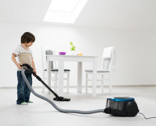 Mały chłopiec robi próżniowe do czyszczenia w domu w pomieszczeniu - Zdjęcie, obraz