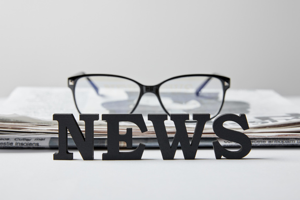 selective focus of news lettering near glasses and newspaper on white  - Foto, imagen