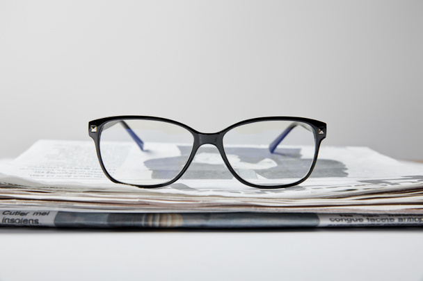selective focus of glasses near newspaper on white  - Foto, Imagem
