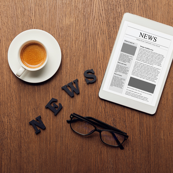 vista superior de la tableta digital cerca de letras de noticias, vasos y taza de café
 - Foto, Imagen