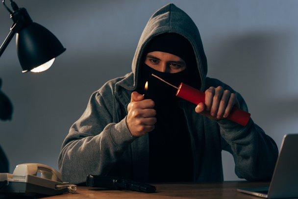 Terrorist in masker en hoodie ontsteken van dynamiet op kamer - Foto, afbeelding