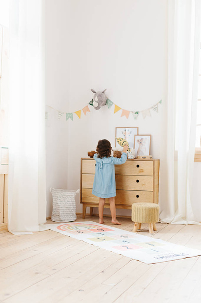 Little girl wearing light blue dress playing in children room scandinavian style. - Foto, immagini