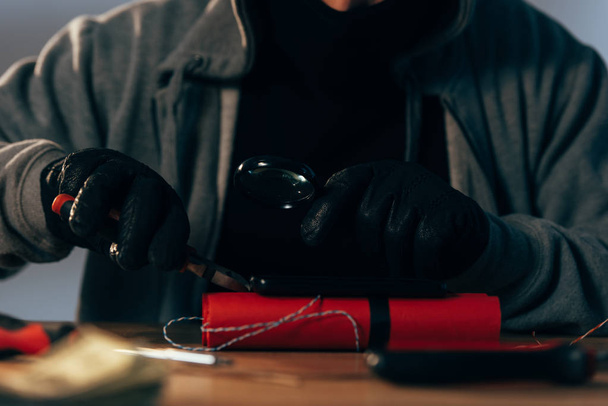Partial view of terrorist in leather gloves making bomb - Фото, изображение