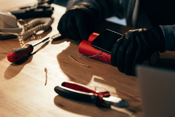 Обрізаний вид терориста в шкіряних рукавичках, що роблять бомбу
 - Фото, зображення