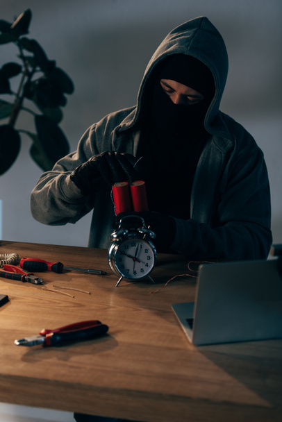 Концентрированный террорист в маске и перчатках делает бомбу в комнате
 - Фото, изображение