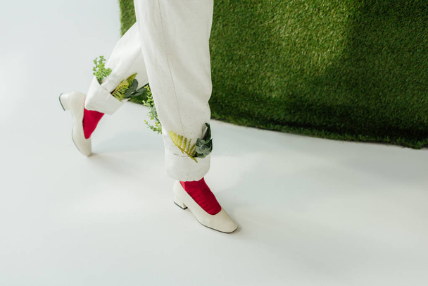 low section of woman in white pants with green leaves and stylish shoes  - 写真・画像