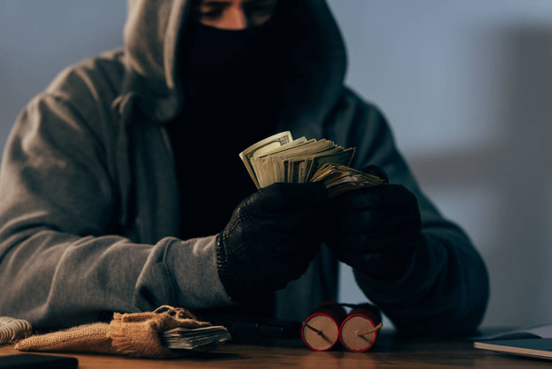 Vista parcial del terrorista enmascarado contando billetes en dólares
  - Foto, Imagen
