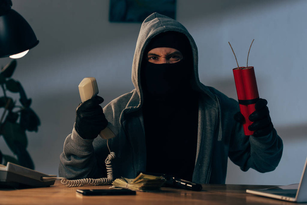 Wütender Terrorist in Maske hält Mobilteil und Dynamit im Zimmer - Foto, Bild