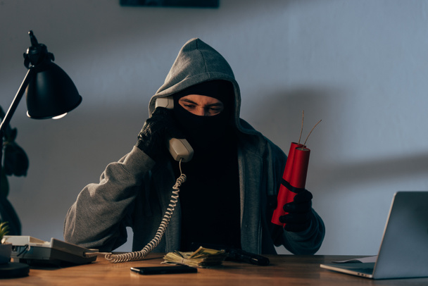 Terrorista en máscara sosteniendo dinamita y hablando por teléfono
 - Foto, imagen