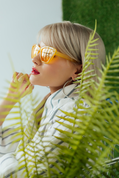 красивая стильная девушка в солнцезащитных очках, позируя возле листьев папоротника
 - Фото, изображение
