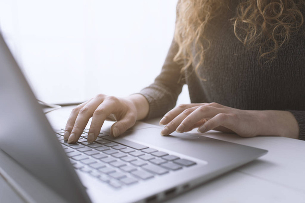 Kobieta siedzi przy biurku i łączy się z laptopem - Zdjęcie, obraz