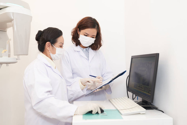 Bilgisayar ekranı ve konuşmak keşfetmek panoramik diş röntgen yan görünüm Asyalı kadınlar Beyaz önlük - Fotoğraf, Görsel