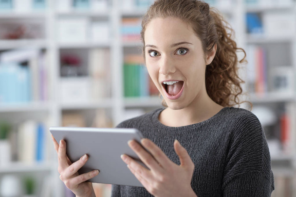 Surprised cheerful girl connecting with her tablet - Фото, изображение