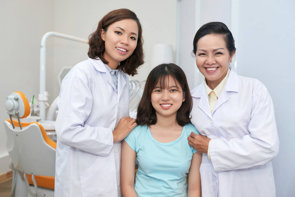 Wesoły Azjatycka Dentyści i urocza dziewczyna w nowoczesne gabinety dentystyczne, na szczęście uśmiecha się do kamery - Zdjęcie, obraz