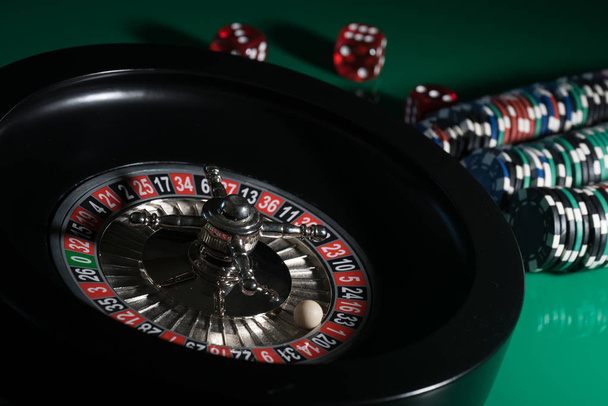 casino background, dice cubes and poker chips on gaming table, roulette wheel in motion - Photo, Image