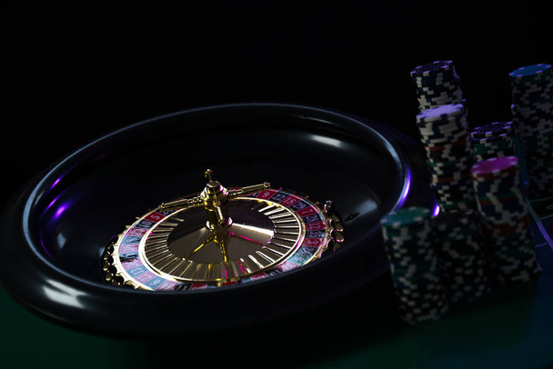  Kasino tausta, Pelimerkit pelipöydällä, rulettipyörä liikkeessä
 - Valokuva, kuva