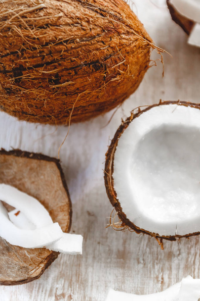 Hele kokosnoot en gehakte in brokken en chips op een licht wit - Foto, afbeelding