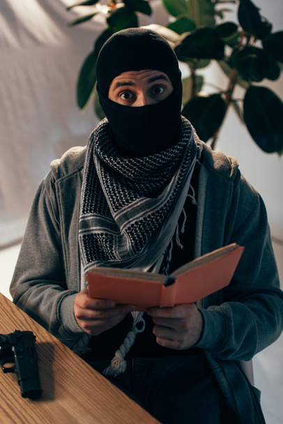 Choc terroriste en noir masque lecture livre à la table
 - Photo, image