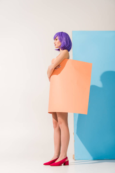 beautiful girl with purple hair covered in coral paper sheet posing on blue and white - 写真・画像