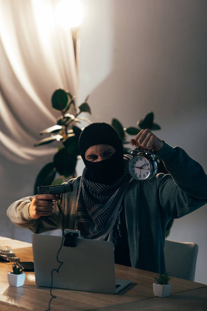 Агрессивный террорист с пистолетом показывает будильник в видеочате
 - Фото, изображение