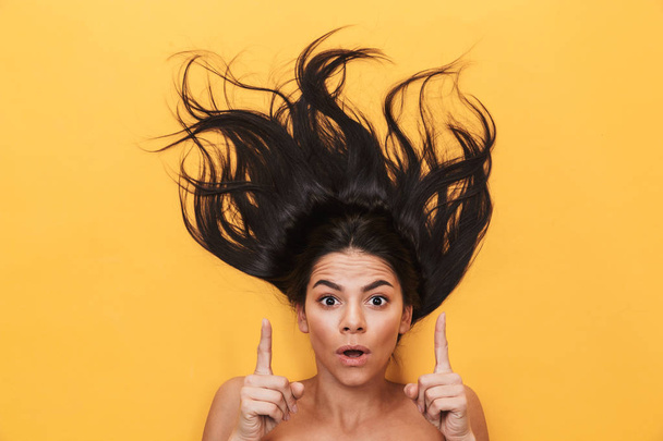 Shocked young woman lies isolated on yellow background. Healthy hair concept. - Fotoğraf, Görsel
