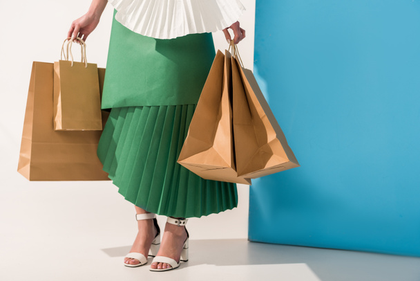 cropped view of stylish girl in paper clothes with shopping bags on blue and white - Foto, Imagem