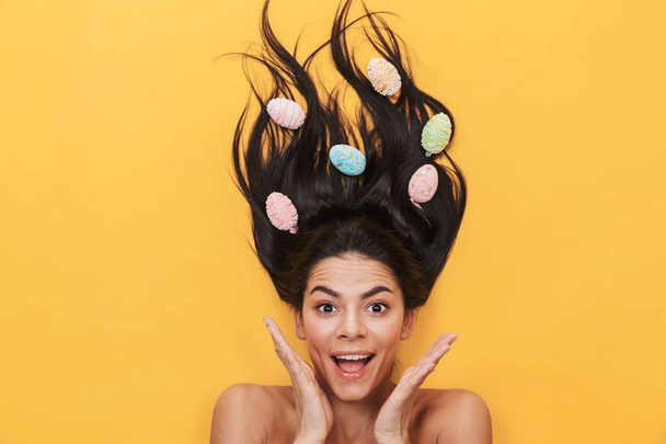 Shocked young woman lies isolated on yellow background over easter eggs. - Valokuva, kuva