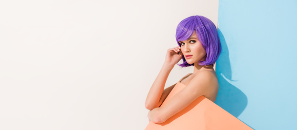 plan panoramique de belle fille aux cheveux violets recouverts de feuille de papier corail posant sur bleu et blanc avec espace de copie
 - Photo, image