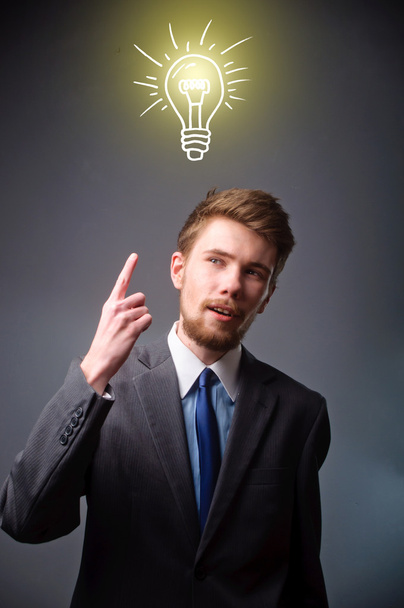 Young businessman with thoughtful expression and light bulb over - Photo, Image