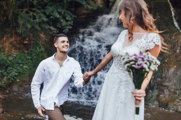 молода красива пара святкує день весілля біля водоспаду
  - Фото, зображення