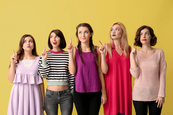Portrait of beautiful women with raised index fingers on color background - Foto, Imagem