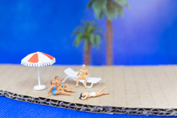 Persone in miniatura che indossano costume da bagno rilassante sulla spiaggia
 - Foto, immagini