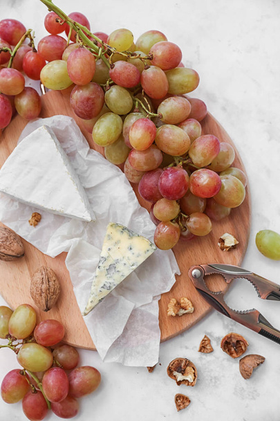 Созревший сочный виноград с сыром и грецким орехом на деревянной доске
 - Фото, изображение