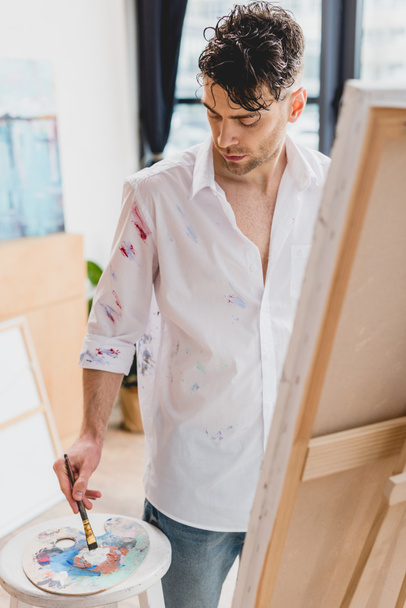 sanatçının palette boya karıştırma boya ile lekeli Beyaz gömlekli seçici odak - Fotoğraf, Görsel