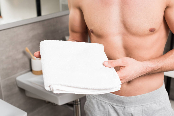cropped view of shirtless man holding white towel in bathroom  - Foto, Bild