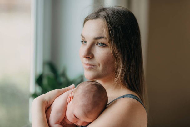 schöne junge Mutter hält sanft neugeborenes Baby - Foto, Bild