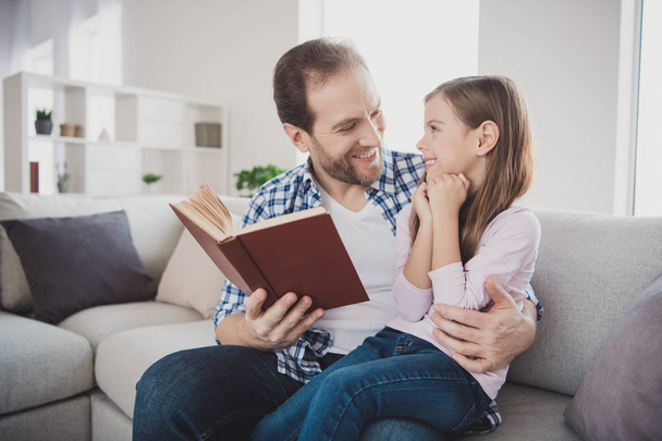 Portrait of his he her she nice cute lovely attractive cheerful cheery positive pre-teen girl handsome bearded dad sitting on divan teaching in modern light white interior room indoors - Foto, Imagem