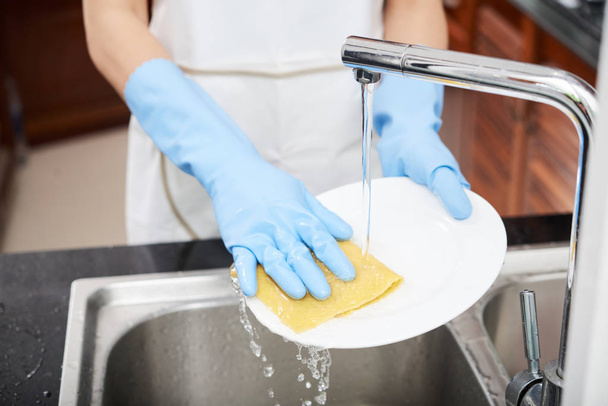 Manos mujer mujer usando guantes al lavar la placa en el fregadero
 - Foto, imagen