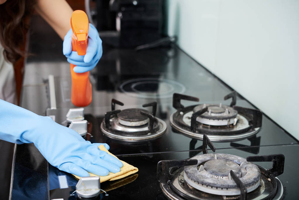 Hands of woman in gloves cleaning stove with professional detergent - Foto, Imagem